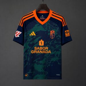 Camiseta de visitante del Granada, temporada 26/27, color verde oscuro camuflaje con ribetes naranjas.